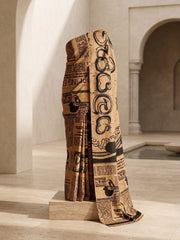 Mustard newspaper print mulmul cotton saree displayed on a stand